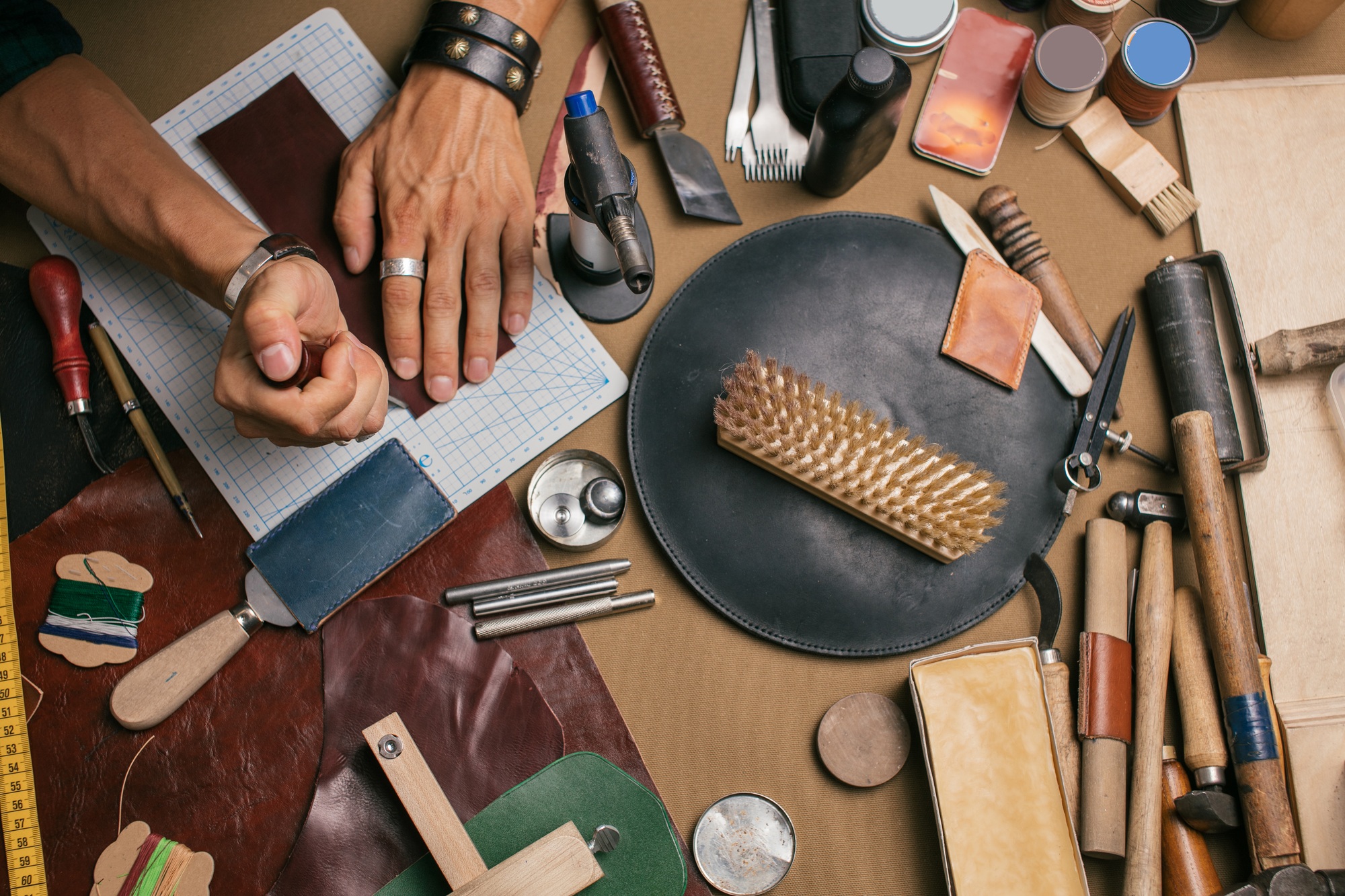 Close up of a shoemaker working with leather textile and hammer at a workshop